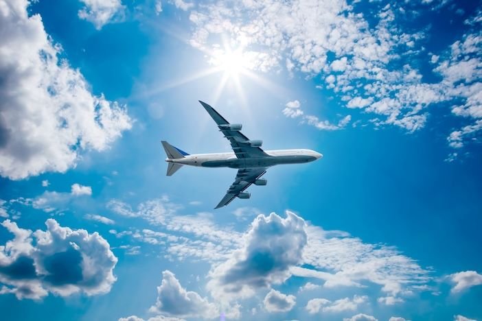 A record start to 2026 as aircraft orders hit six-year high Airplane in the blue sky with clouds from below, high flying passenger plane. jet plane flying overhead diagonally in sky with sunlight. Bottom view