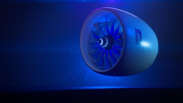 Rolls-Royce UltraFan engine concept displayed under dramatic blue lighting, showing the large-diameter fan and nacelle with the Rolls-Royce logo visible on the casing