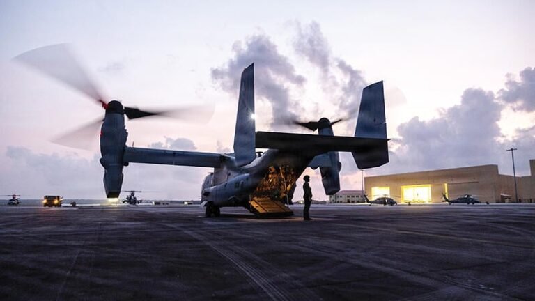 Person standing by V-22 on runway