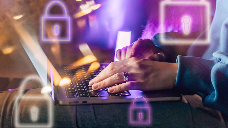 Female hands typing on a laptop in neon light. A lock as a symbol of cybersecurity on a foreground