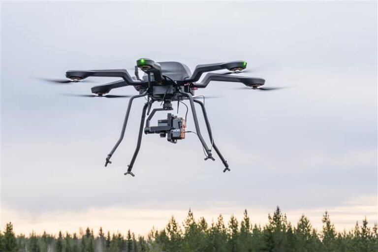 A hexacopter drone equipped with a hyperspectral camera in flight over the tree line at VTT's test site in Finland
