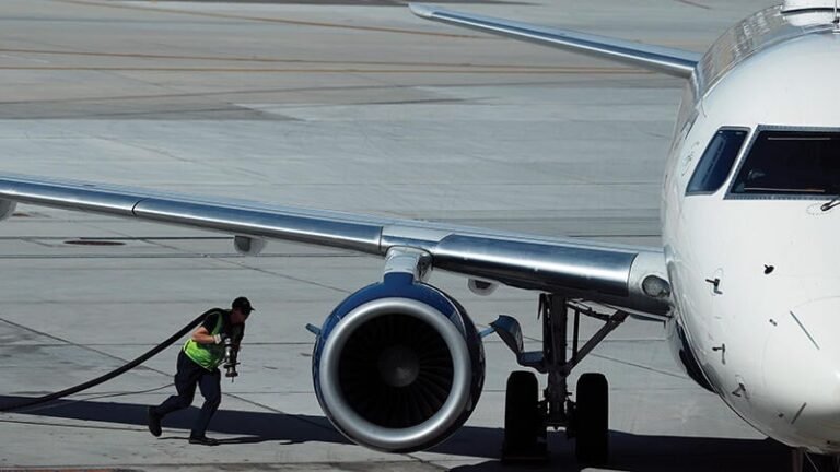 worker carrying refueling hose to aircraft