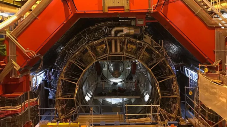 Large Hadron Collider gives scientists their best look yet at conditions right after the Big Bang A metal semicircle structure wit lots of wires and a red structure above.