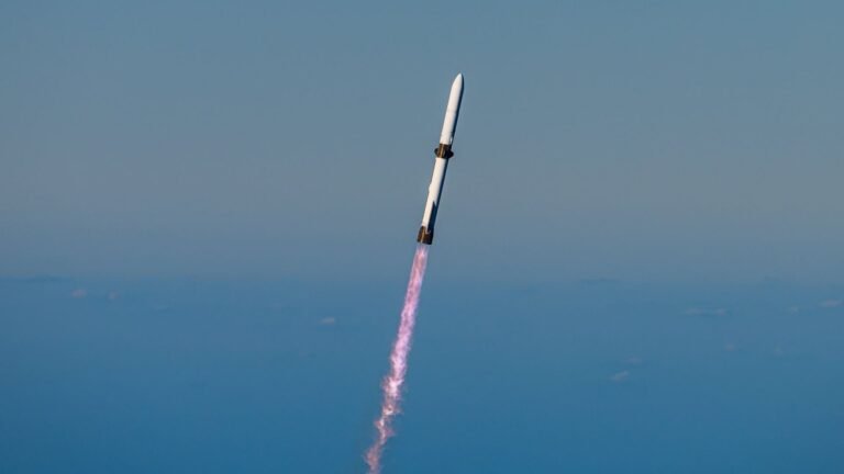 a large white rocket launches into a blue sky