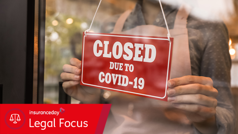 Woman putting red sign with words "Closed Due To Covid-19" onto glass door, closeup