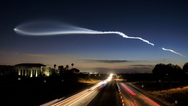 SpaceX Starlink and other satellite megaconstellations are creating an ‘unregulated geoengineering experiment’, scientists say a streak of white gas stretches across a nearly dark twilight sky above a freeway lined with palm trees