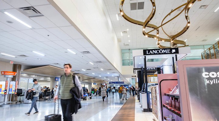 DFW International adds local and national brands to concessions line-up The DFW International concourse with passengers walking past a range of concessions.