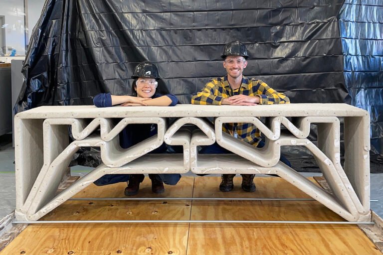 MIT Department of Civil and Environmental Engineering postdoc Hajin Kim-Tackowiak (left) and graduate student Zane Schemmer pose with the 3D printed concrete bridge they designed and load-tested. Photo via MIT.