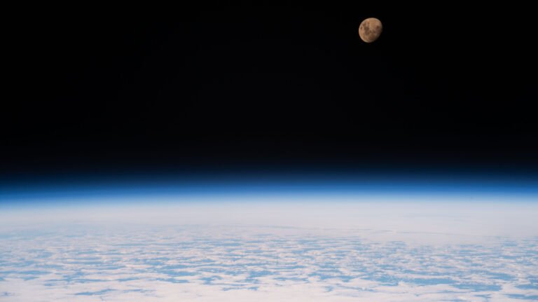 Waxing Gibbous Moon – NASA A view of the Moon from the International Space Station as it orbited 264 miles above a partly cloudy Indian Ocean southeast of Madagascar. The Moon has a golden glow to it, appearing more bronze than its usual gray. It stands out against the darkness of space, while below, Earth's atmosphere glows blue. Below that, we can see white clouds covering up most of the water below.