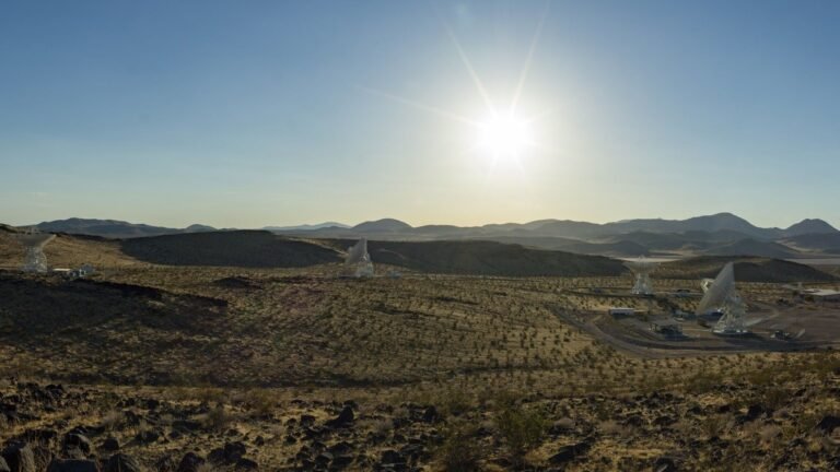 several antennas sit under a blue sky and blazing sun.
