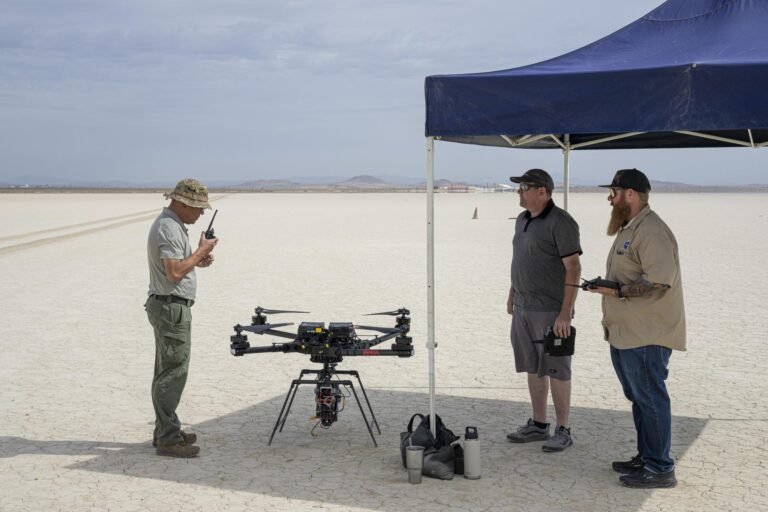 Passion Meets Precision at NASA’s Flight Research Lab One man communicates with a hand-held radio, as two other men wait to the side for the go-ahead command to fly an experiment on a drone.