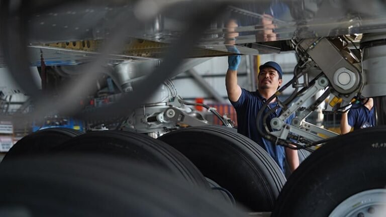 technician inspecting landing gear and underside of an aircraft wing