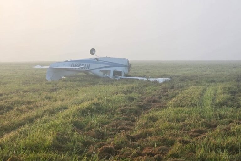 Pilot survives Cessna crash after engine falls off Small white airplane wreck on a grassy field upside down with a wing broken in a foggy morning