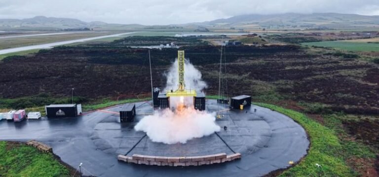 A Skyrora test vehicle fires on a vertical static test stand on a circular pad, throwing up a plume of exhaust and steam, with the Scottish landscape behind