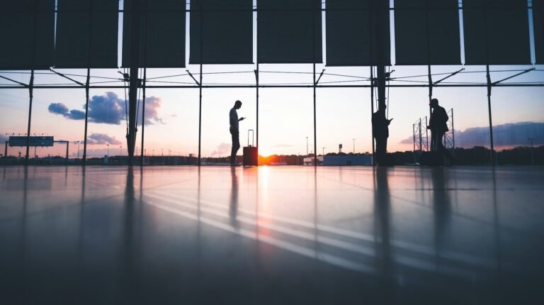 UK seeks airport security innovations in new open call Silhouette of a man standing in a quiet airport terminal with glass window behind him.
